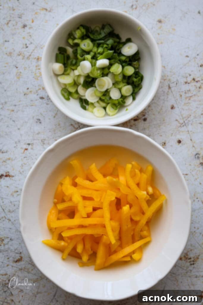 Bright yellow bell pepper sliced into 2-inch strips and fresh green onions thinly sliced, both prepped for stir-frying.