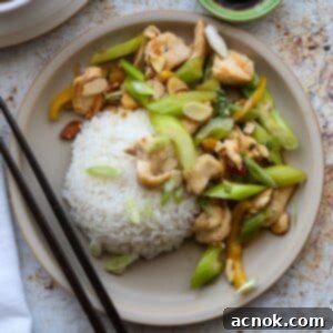 Square photo of a delicious almond chicken stir-fry served with steamed rice in a bowl.