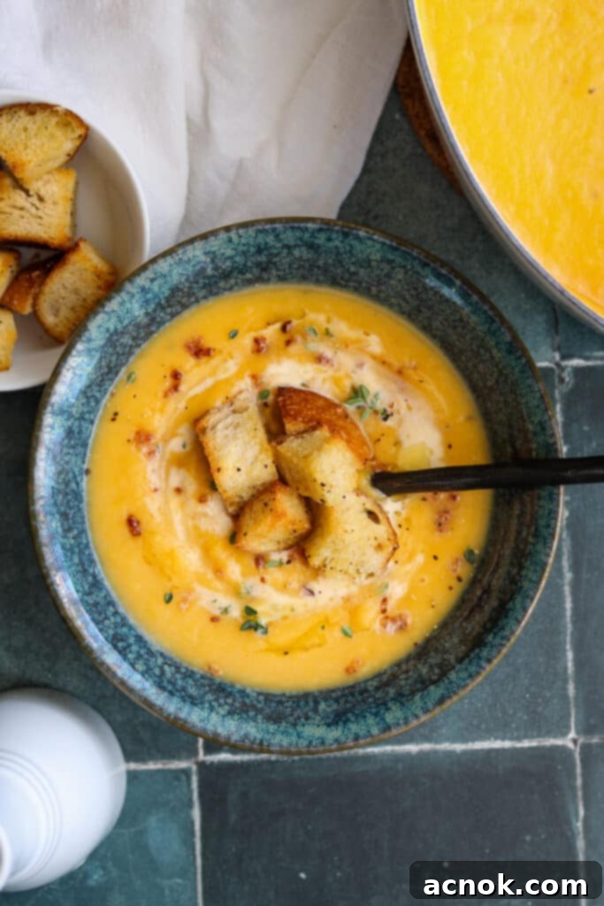 Creamy roasted butternut squash soup garnished with crunchy croutons, crispy bacon pieces, and a delicate drizzle of cream and olive oil.