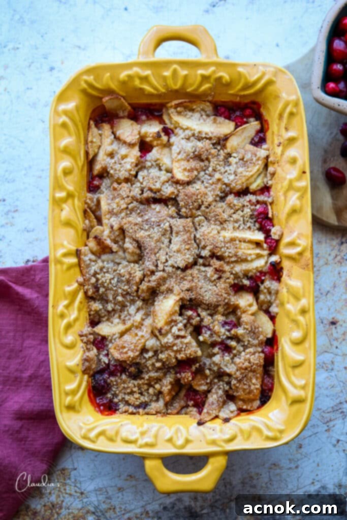 Warm apple cranberry crumble in a yellow baking dish, ready to serve