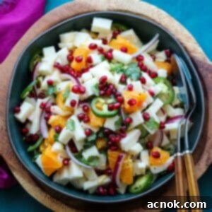 close up image of jicama orange salad in green bowl with serving utensils