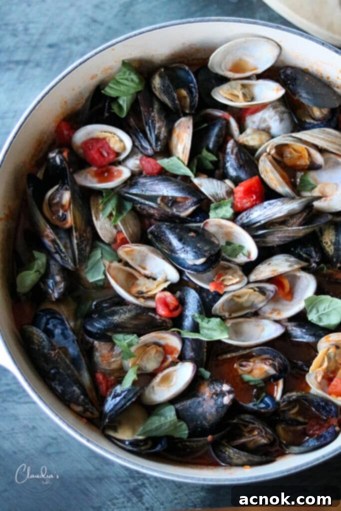 Mussels and clams simmering in a rich tomato broth in a Dutch oven, ready to be served.