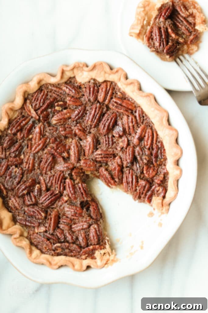 A slice of warm brown butter bourbon pecan pie with a perfectly golden crust and rich, glistening filling, ready to be served.