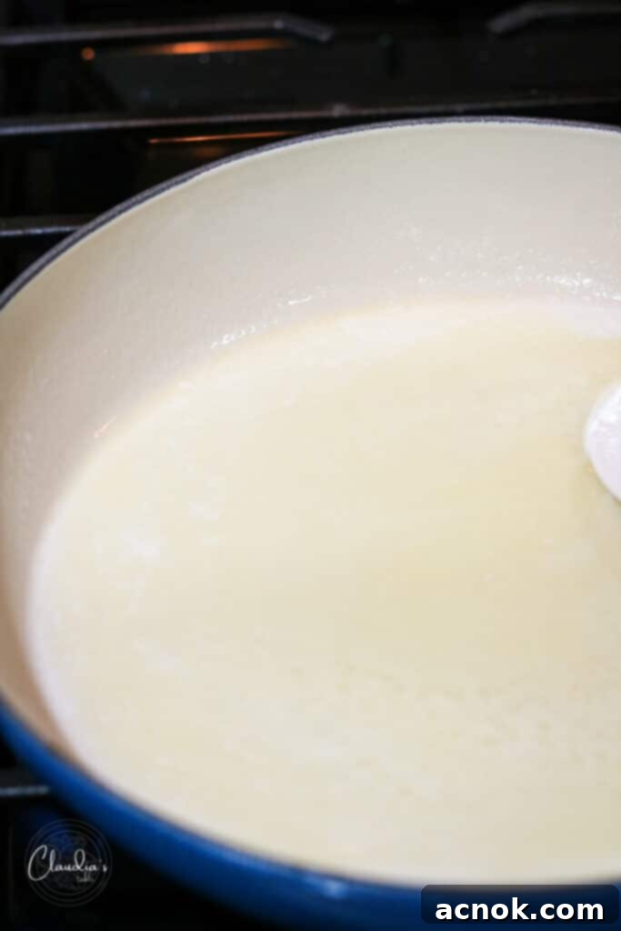 Butter continuing to melt and froth in the pan, with milk solids beginning to break down.