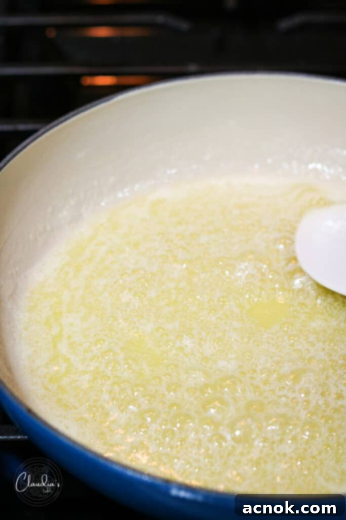 Close-up of butter with milk solids starting to caramelize at the bottom of the pan, developing a nutty fragrance.
