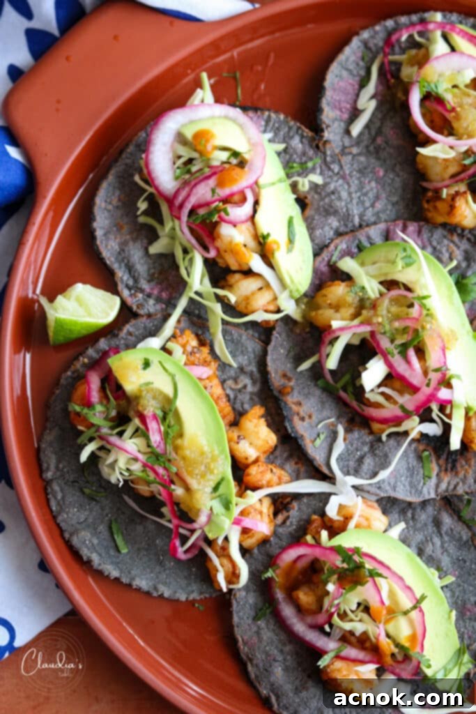 platter of spicy shrimp tacos with pickled red onions, avocado, shredded cabbage and salsa verde