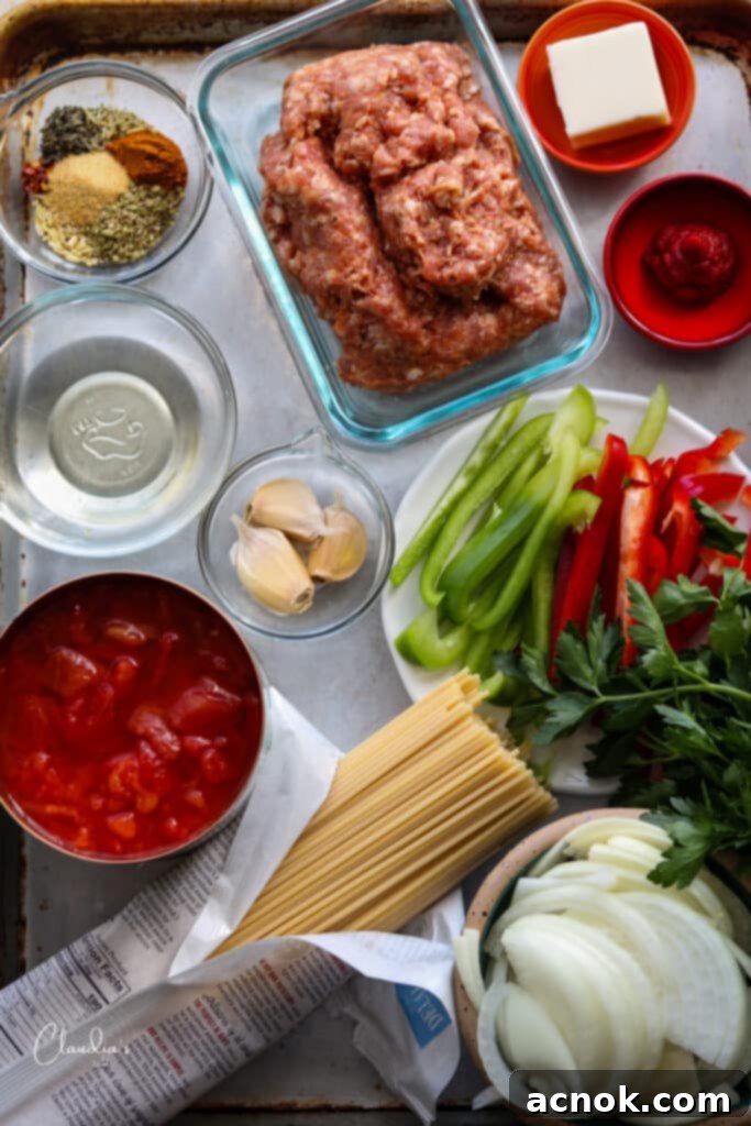 All the fresh ingredients and spices for spicy sausage spaghetti laid out on a sheet pan.