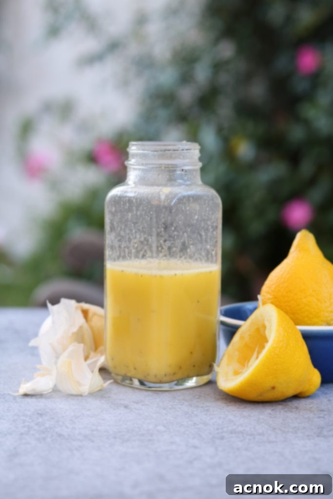 Freshly made Easy Lemon Dijon Dressing in a glass jar, perfectly emulsified and ready to drizzle over a fresh salad.