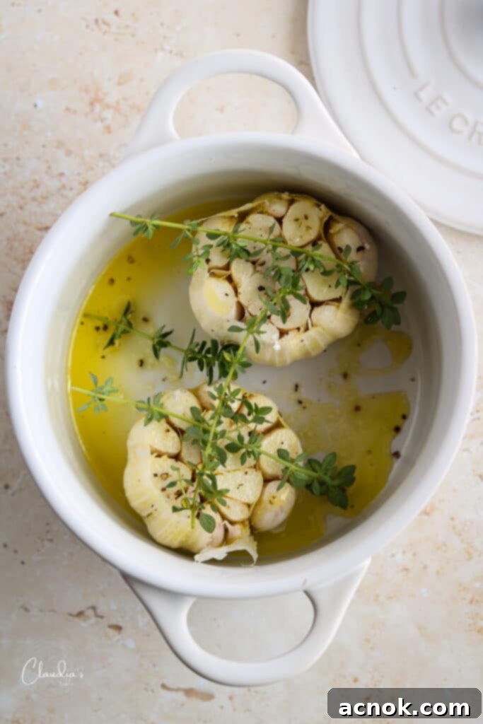 Raw garlic head prepared for roasting with olive oil, thyme, salt, and pepper