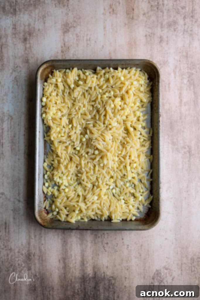 Cooling the cooked orzo on a rimmed baking sheet