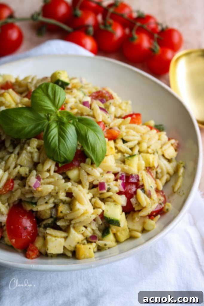 Close up of orzo pesto salad with basil garnish in white bowl