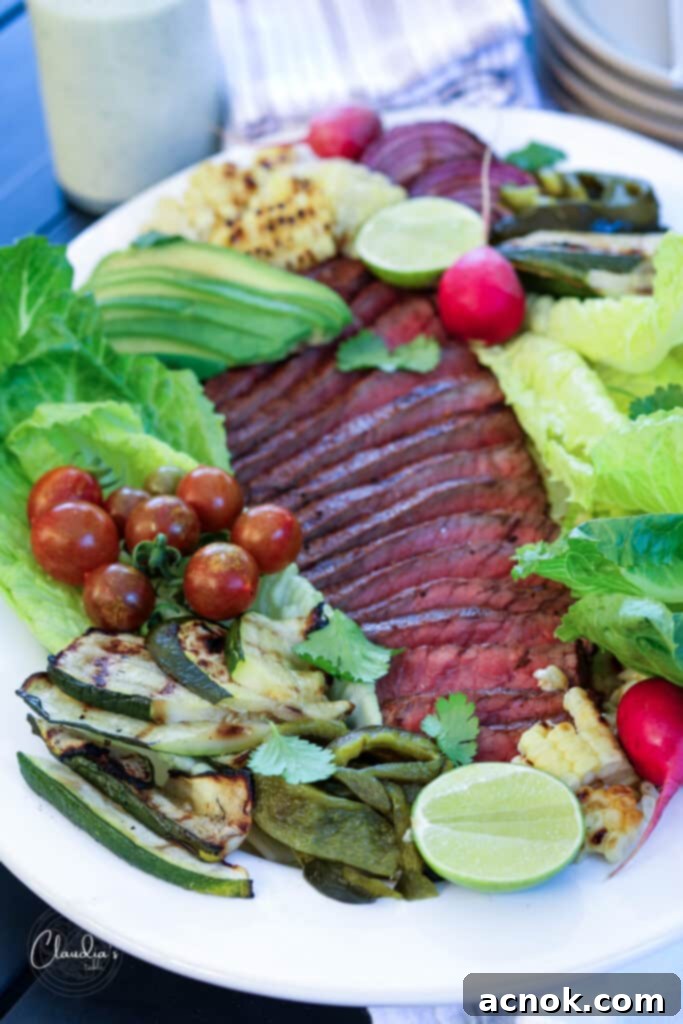 close up grilled steak salad with corn, zucchini , tomatoes, peppers, radish and avocado