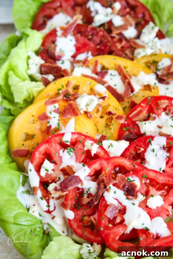 Close-up of a plated BLT salad, showing crispy bacon, blue cheese crumbles, and vibrant tomatoes on butter lettuce