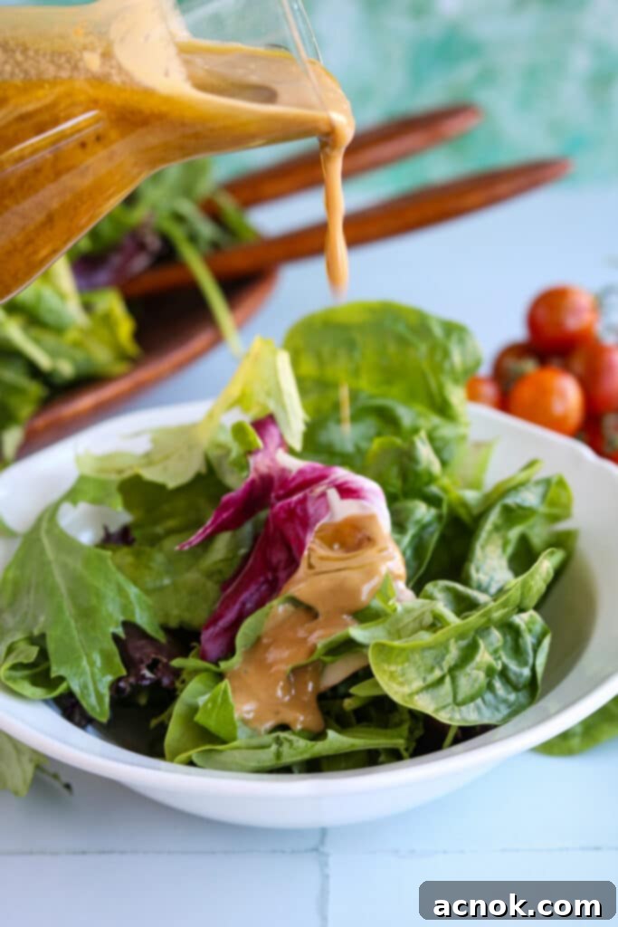 Balsamic vinaigrette drizzled generously over fresh salad greens, ready to be tossed.