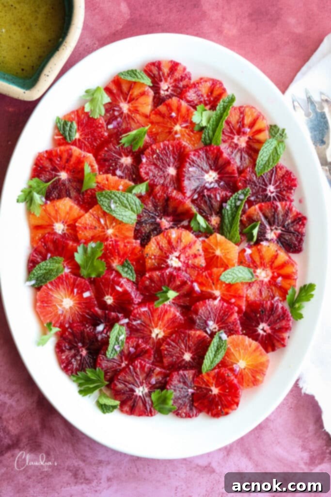 Top view of blood orange salad with fresh herbs and red onion slices.