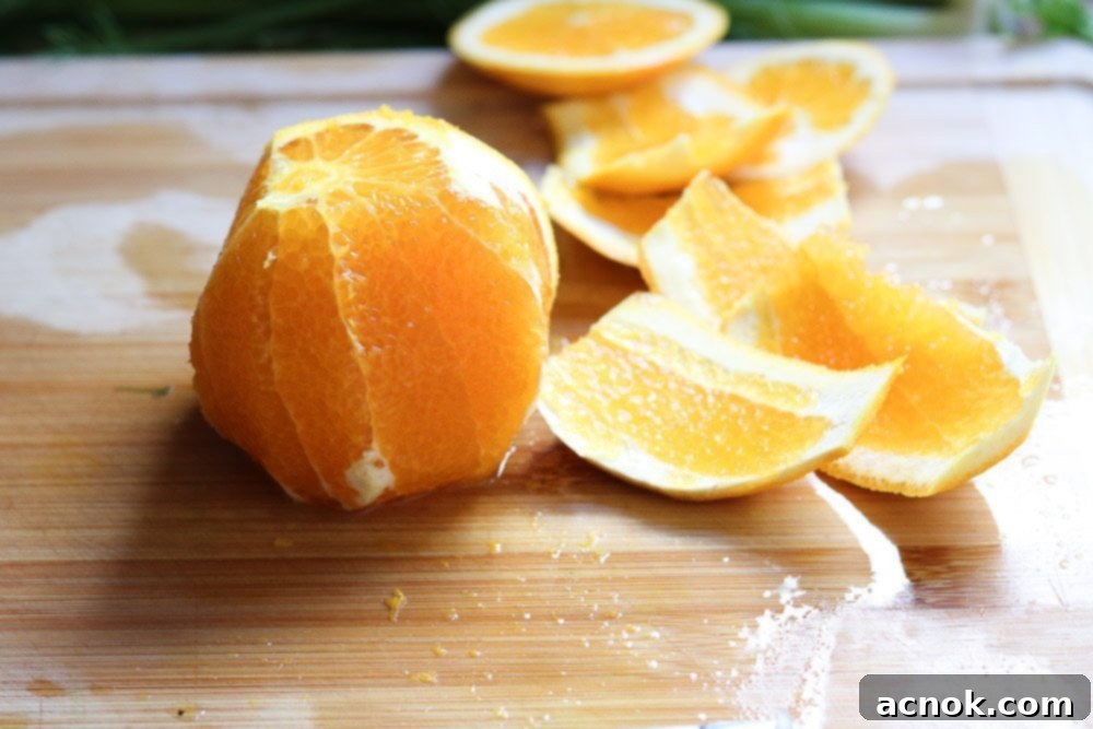 A hand slicing the skin and pith off a blood orange on a cutting board.