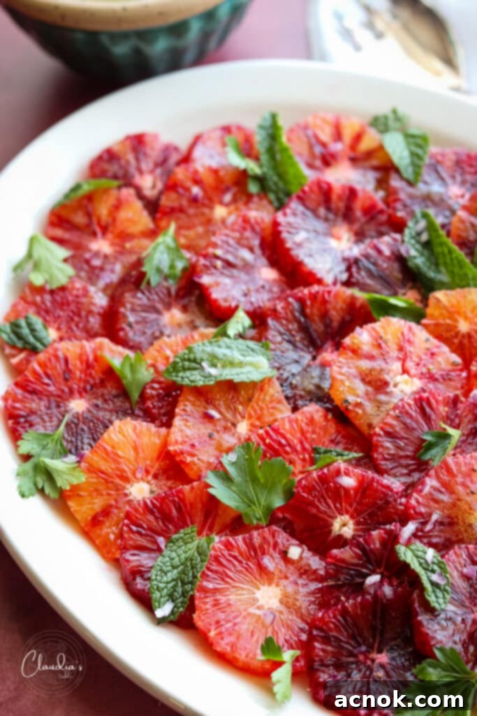 Close-up of a finished blood orange salad with herbs and red onion on a platter.