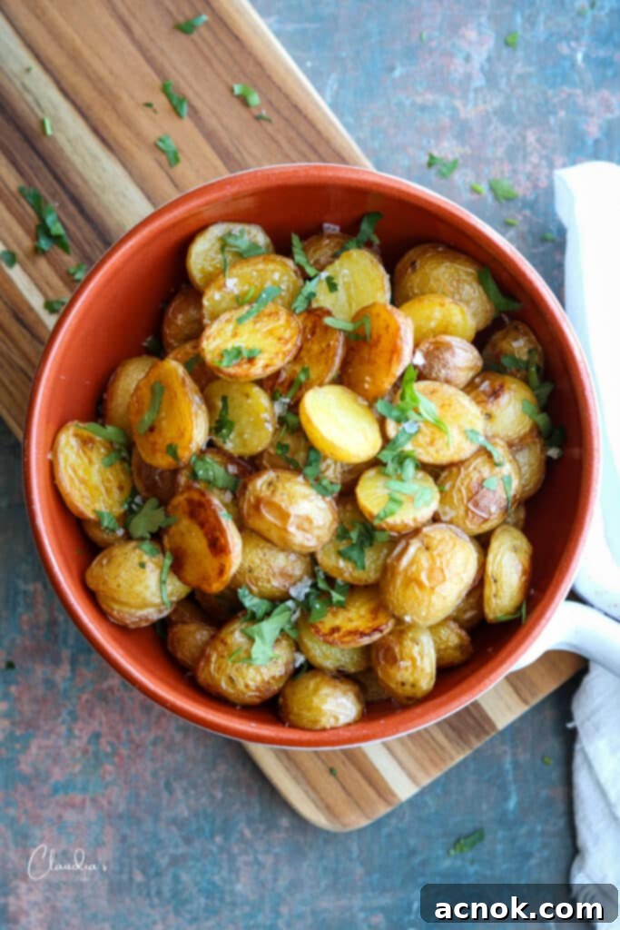 Crispy oven roasted potatoes in serving dish, garnished with fresh parsley.