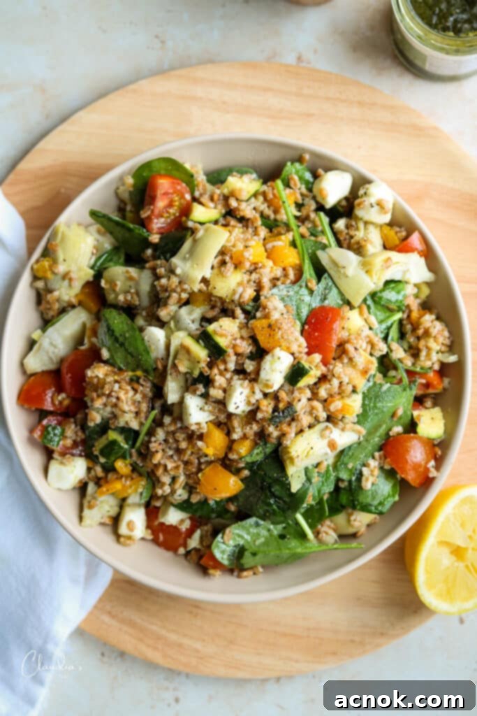 Farro salad with pesto and vegetables presented in a beautiful beige bowl, ideal for summer gatherings.