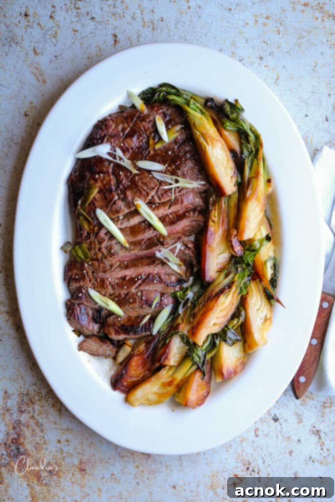 Succulent Grilled Asian Flank Steak 2 Asian marinated grilled flank steak on white platter with stir fried bok choy